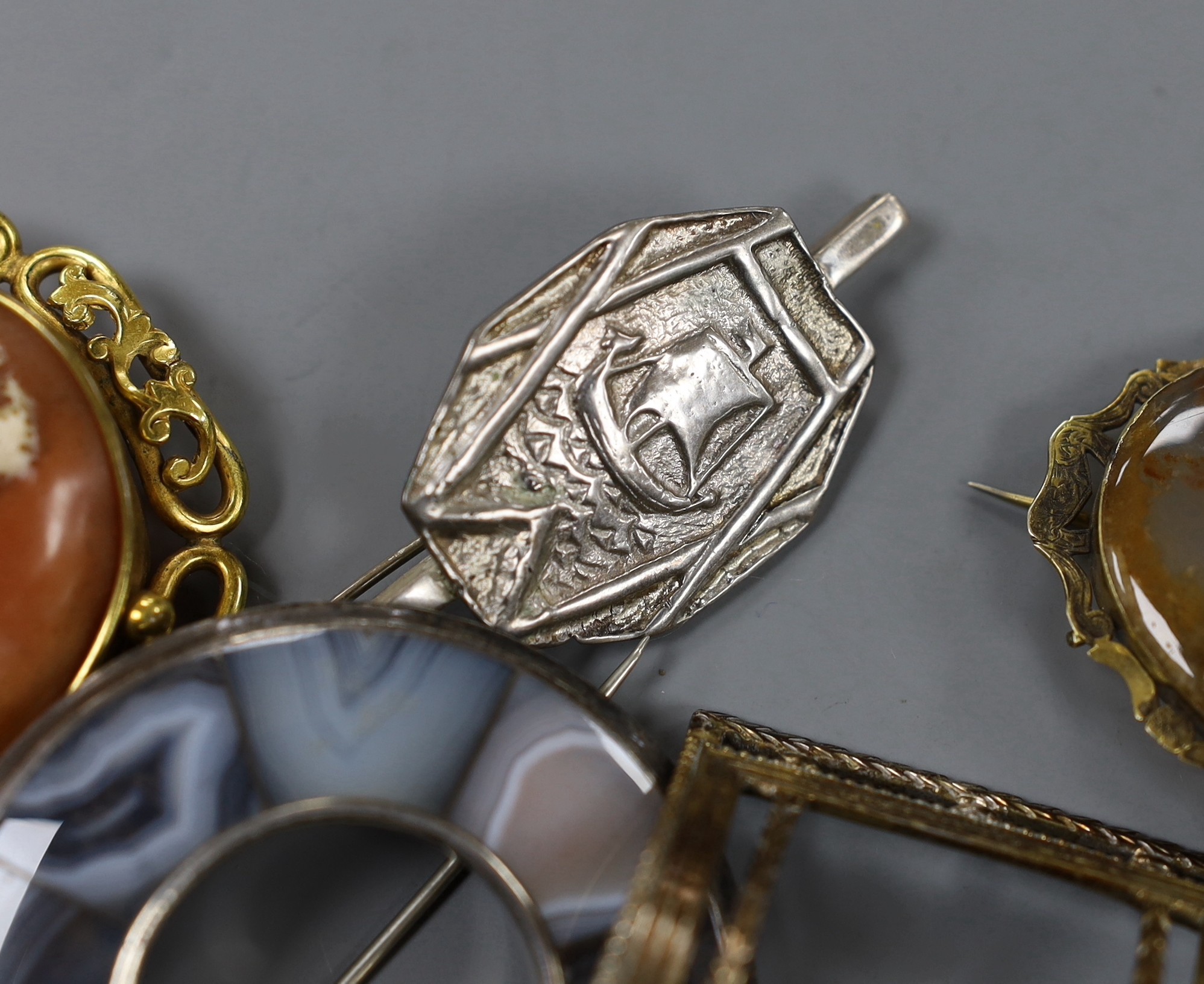 A mixed group of jewellery including a Victorian yellow metal and gem set oval brooch, a filigree white metal and enamel peacock brooch, a white metal and paste set swallow brooch, Scottish hardstone set brooch, pinchbec